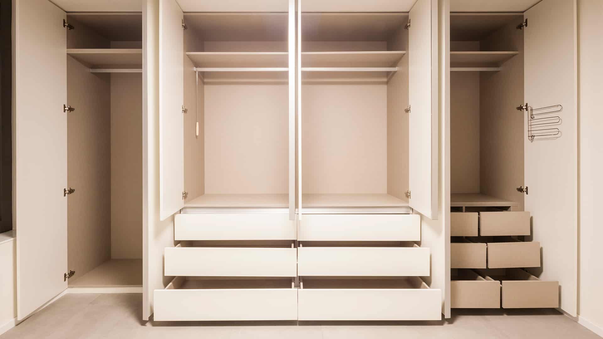 Otwarta biała pusta szafa w zabudowie z wysuniętymi szufladami