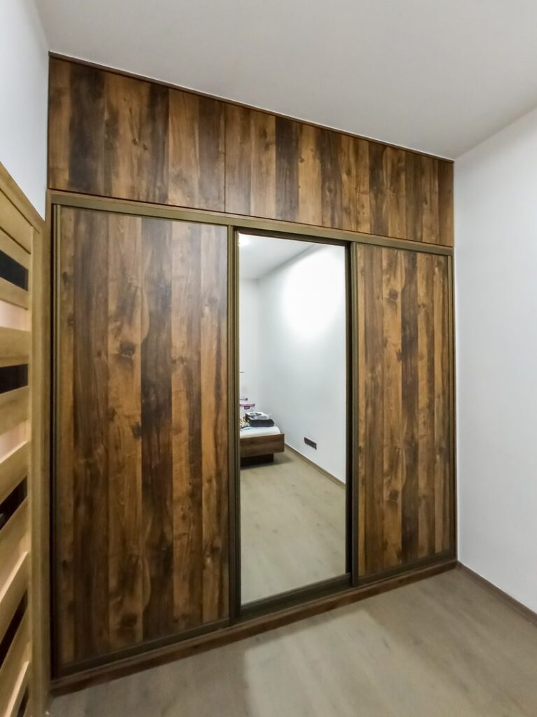 Zamknięta szafa drewnopodobna z drzwiami przesuwnymi i lustrem