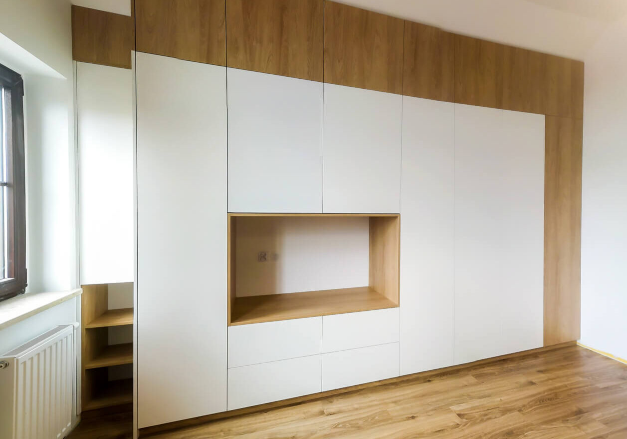 Biała szafa z miejscem na TV i wstawkami drewnianymi na szerokość pokoju