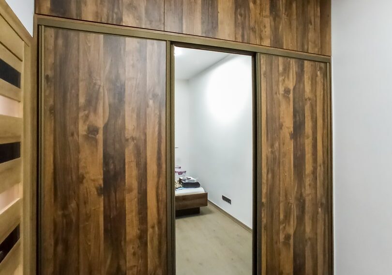Zamknięta szafa drewnopodobna z drzwiami przesuwnymi i lustrem